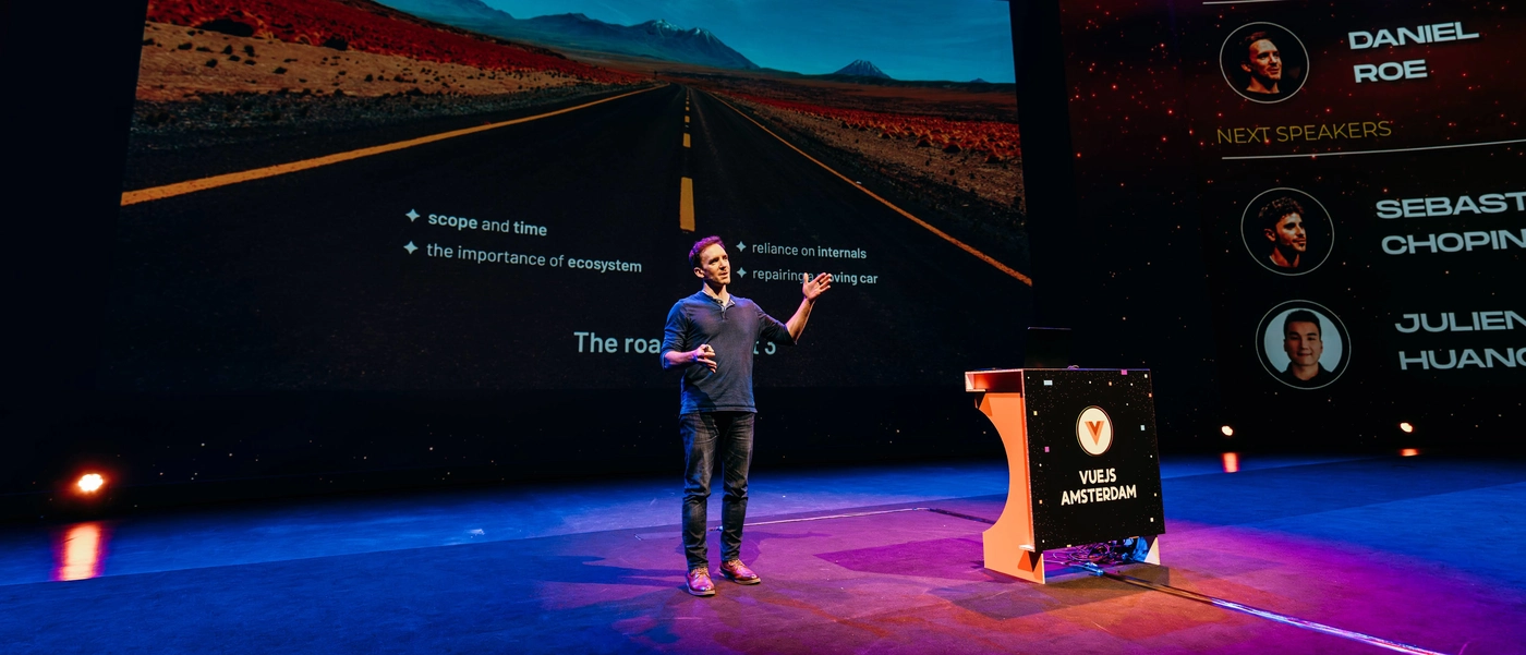 Daniel Roe speaking in front of a very large screen